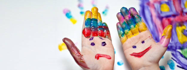 Zwei Hände, auf die mit Fingerfarben ein lachendes und ein trauriges Gesicht gemalt ist